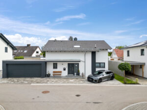 Neues Haus mit Garage und Auto vorne.